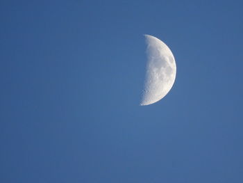 Low angle view of half moon against clear blue sky