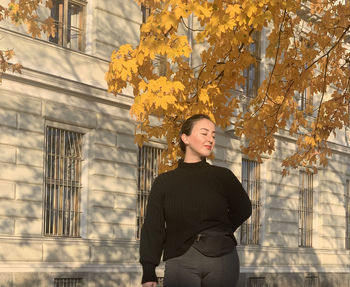 Portrait of young woman standing against wall