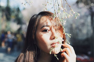 Close-up portrait of young woman with flower buds at park