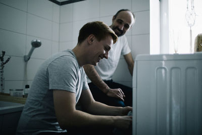 Smiling man by parent near washing machine at home