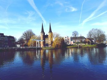 Buildings by river against blue sky