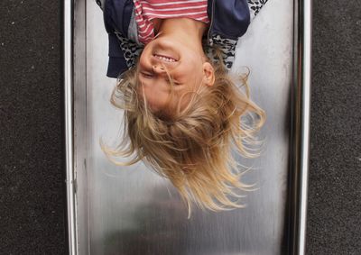 Upside down image of smiling girl enjoying on slide