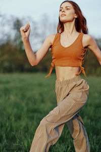 Portrait of young woman exercising on field