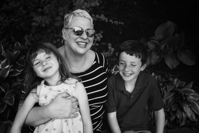 Smiling mother with children against plants