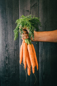 Close-up of man holding vegetables against orange background