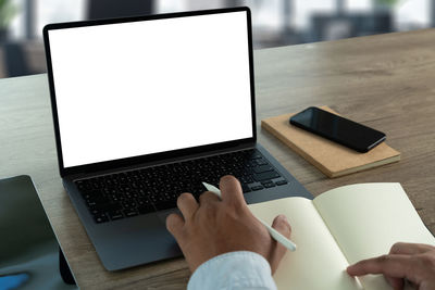 Cropped hands using laptop on table