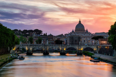 Arch bridge over river against buildings in city