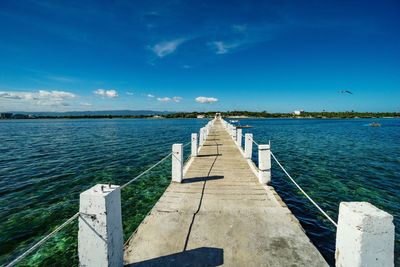 Pier over sea against blue sky