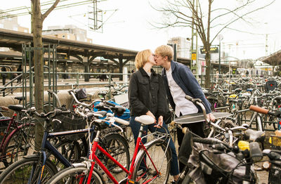 Young couple kissing while standing at bicycle parking station