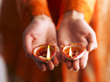 Midsection of woman holding diyas
