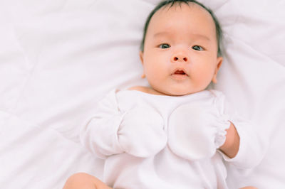 Portrait of cute baby lying on bed