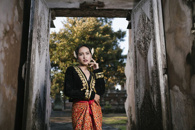 Portrait of beautiful woman wearing traditional clothing standing at doorway