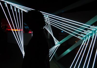 Midsection of man standing against illuminated building at night