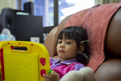 Cute girl with electrodes on head relaxing on chair