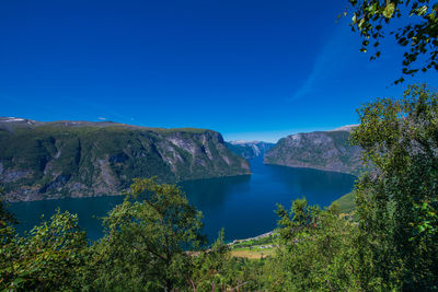 Scenic view of lake and mountains against clear blue sky