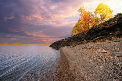 Rock formation on beach against sky during sunset