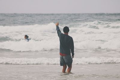 Rear view of friends splashing water at beach
