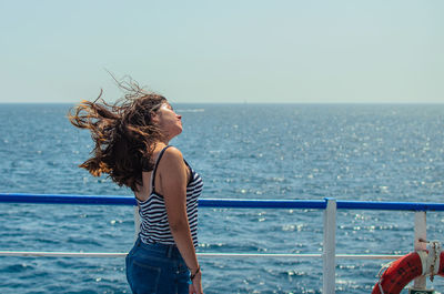 Woman standing by sea against sky