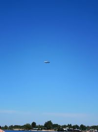 Low angle view of airplane flying against clear blue sky