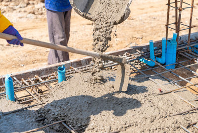 Worker using hoe to spread concrete on the floor in construction site