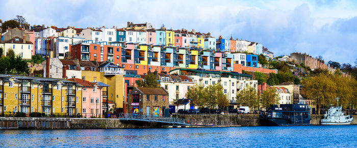 Buildings by river against sky in town