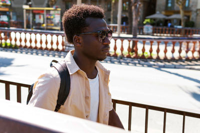 Portrait of young man standing by railing