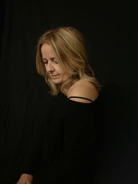 Young woman looking away against black background