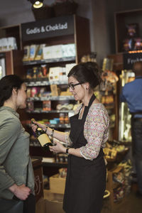 Owner showing bottle to customer at store