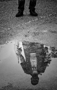 Low section of man standing on puddle