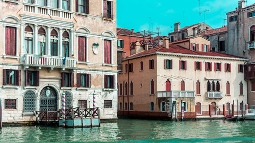 Buildings by canal against sky in city