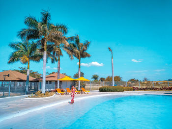 People swimming in pool by sea against sky