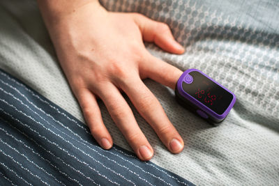 Overhead view of a hand with a pulse oximeter on the finger.