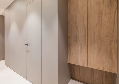 Apartment corridor with wooden wardrobe and grey panel walls with door.