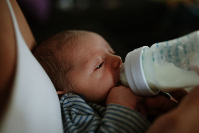 Midsection of woman feeding milk to newborn son