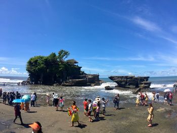 People at beach against blue sky