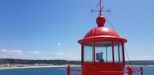 Lighthouse by sea against blue sky