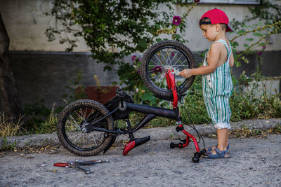 Side view of boy standing by bicycle