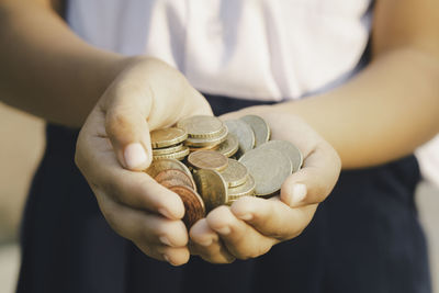 Midsection of girl holding coins outdoors