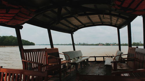 Empty chairs and table at beach against sky