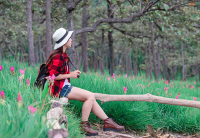 Woman sitting on chair against trees