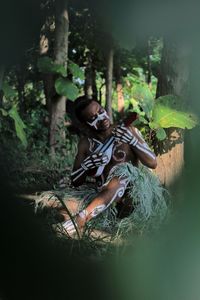 Woman sitting on field in forest