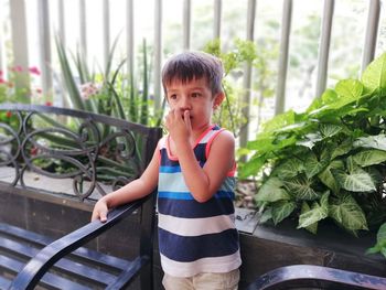 Thoughtful boy standing against plants