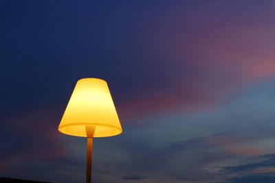 Low angle view of illuminated lamp against sky at sunset