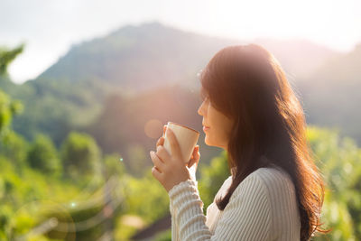 Close-up of woman holding tree against mountain