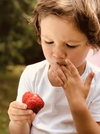 Little girl eating red strawberry and finger in the mouth 