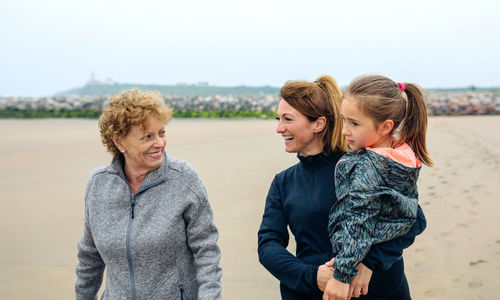 Smiling women and girl walking on beach