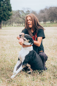 Woman with dog sitting on field