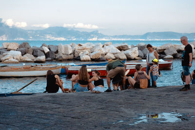 Group of people talking and seated at the sea coast of naples