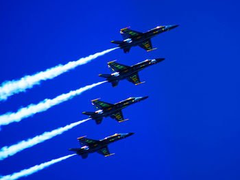 Low angle view of airplane flying against blue sky