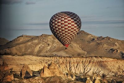 Hot air balloon flying over desert against sky during sunset